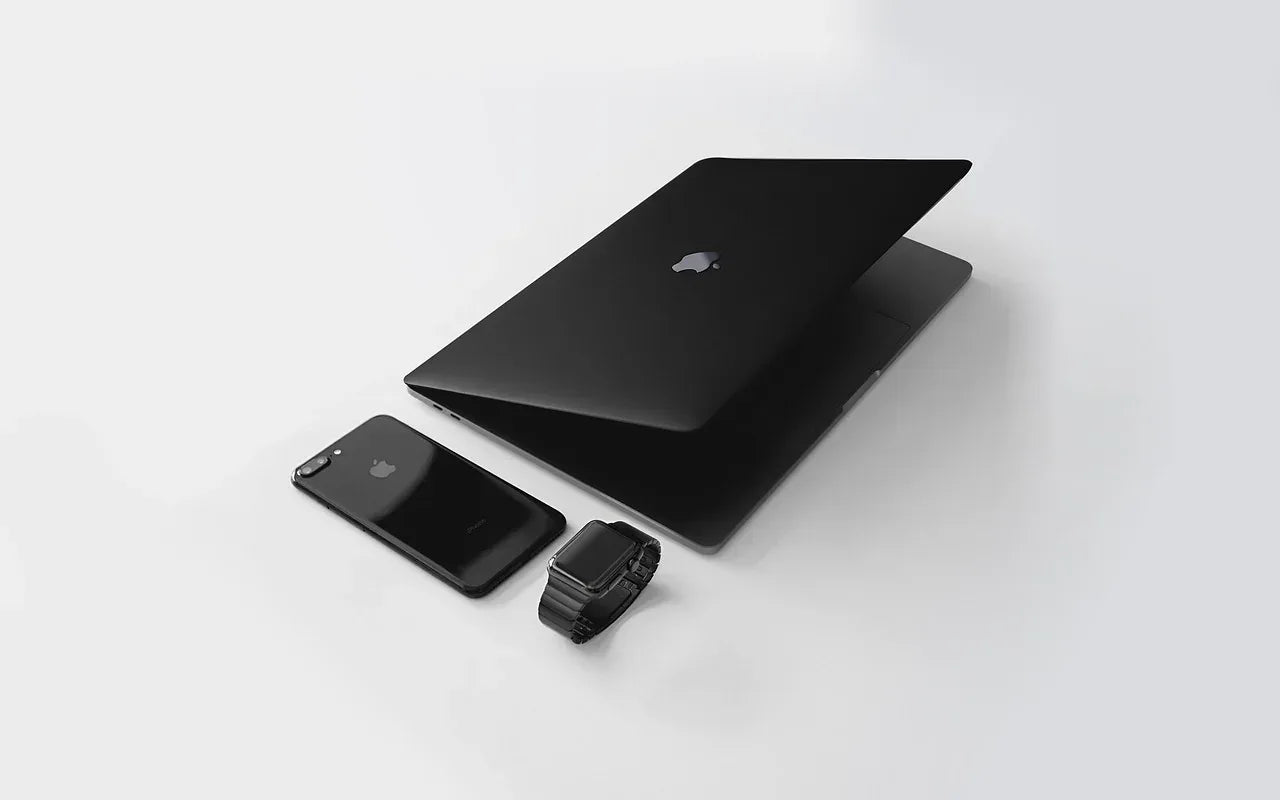 Black laptop, phone, and camera on a white background